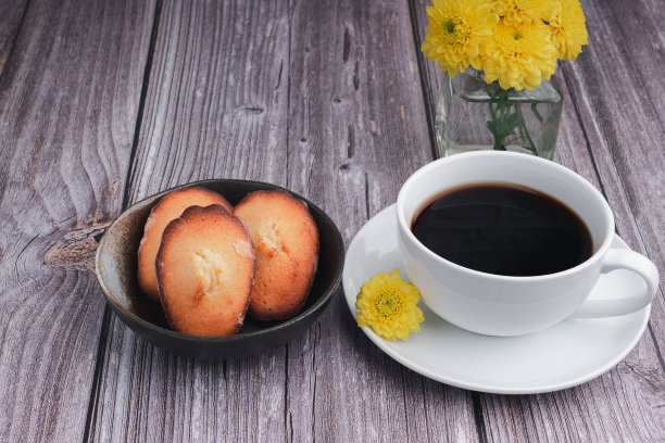 新鲜的玛德琳蛋糕，自制的传统法式小饼干，白色咖啡杯放在木桌上。图片下载