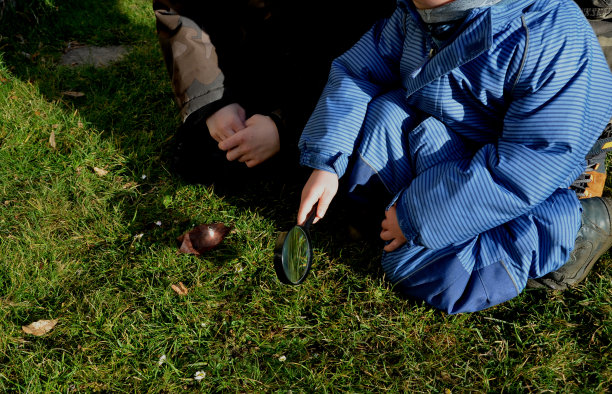 玩丛林工艺品的粗野男孩。他们用放大镜生火。镜头的焦点会将太阳光集中成一个点，树叶或干草就会燃烧起来图片下载