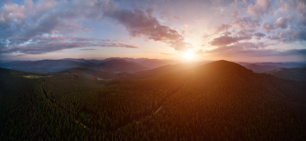 在美丽多云的天空下，有树木的山。图片下载