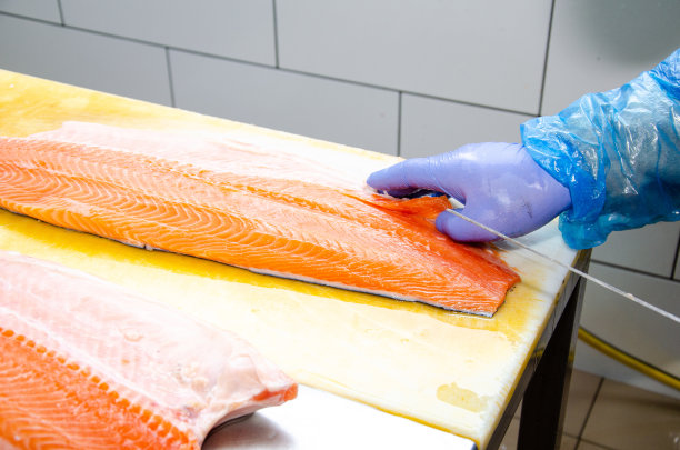 鲑鱼。一位师傅在切鲑鱼。健康食用红鲑鱼。鱼类生产照片。图片下载