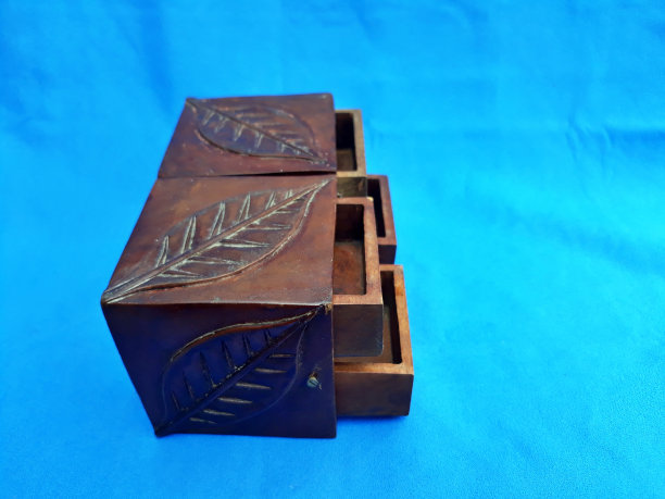 封闭的小木箱货架存储，如一个抽屉雕刻的树叶图案孤立在蓝色背景。静物装饰艺术图片下载