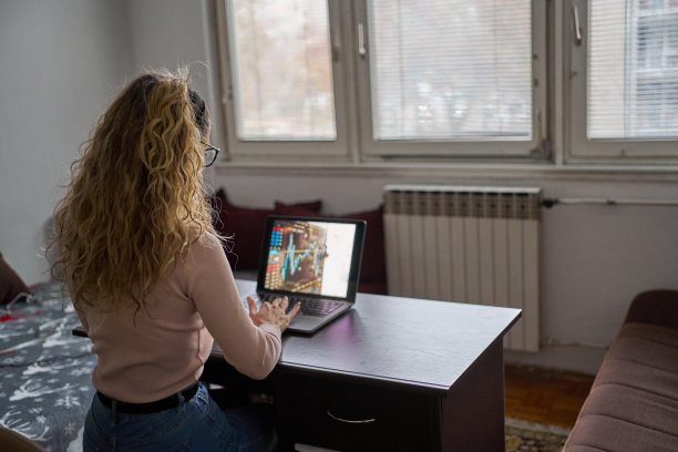 年轻女子坐在桌子旁，用笔记本电脑，看着屏幕，在家工作图片下载