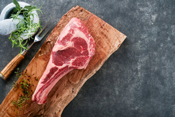 新鲜的生牛排。干燥陈年生战斧牛排加香草和盐在旧木头背景上。准备烧烤。俯视图和复制空间。图片下载