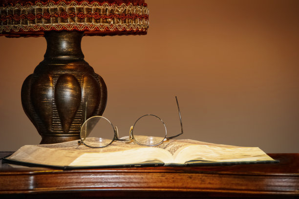 老式的台灯在桌子上，旁边是打开的书，上面放着眼镜——复印的空间图片下载