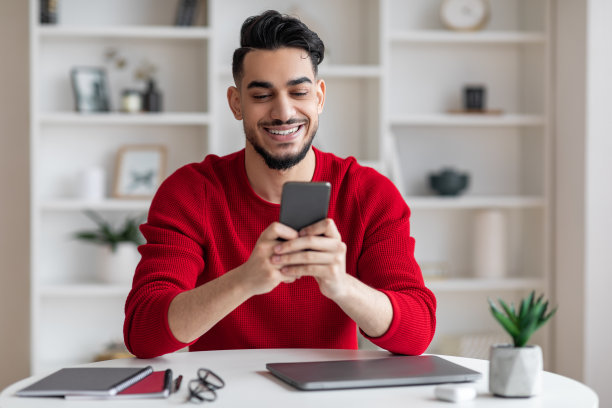 在家庭办公室使用智能手机的阿拉伯男性自由职业者图片下载