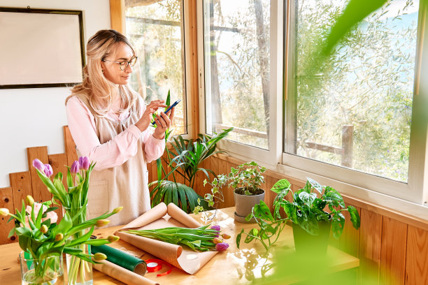 花店女花匠用智能手机接单。花交付。小型企业的社交媒体。图片下载
