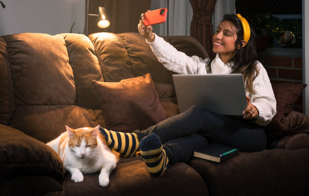 一位拉丁妇女和她睡在沙发上的猫拍了一张自拍照图片下载