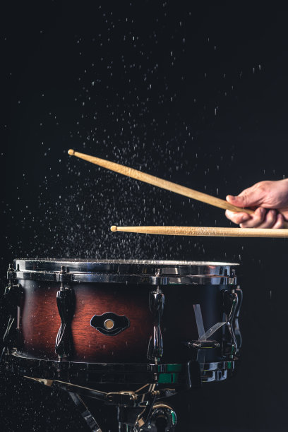 一个男人在黑暗的背景下演奏小军鼓。图片下载