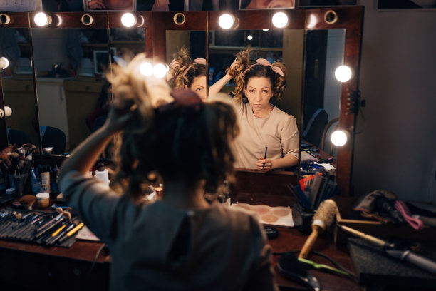 在剧场后台，坐在镜子前的女演员正在整理头发图片下载