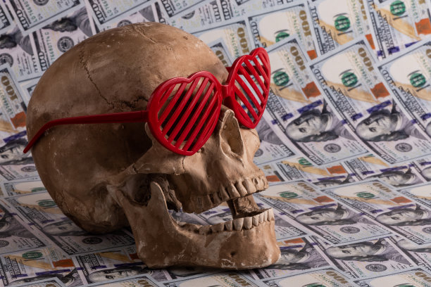 在美元的背景上，人类头骨和心形的太阳镜图片下载