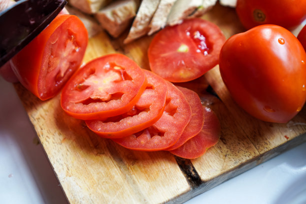 这张特写照片显示，一户家庭厨房的木砧板上排列着新鲜切片的西红柿。图片下载