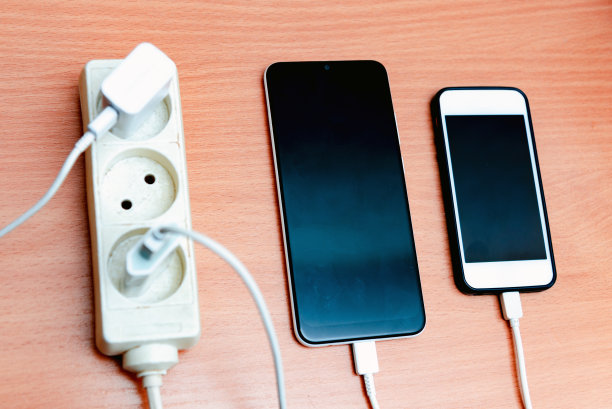 在木桌上插入智能手机的电源插座、适配器、电源线充电器。智能手机充电。图片下载