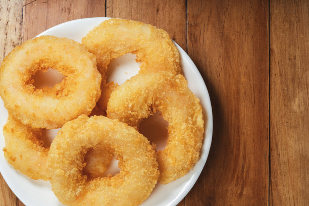 木桌上白色盘子里的炸虾甜甜圈。图片下载