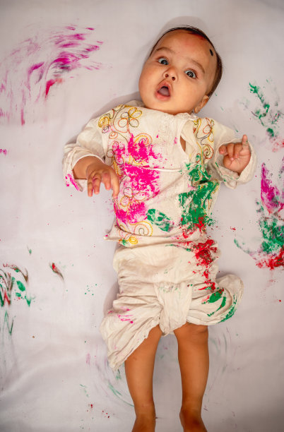 婴儿躺在床上，从顶部角度看，穿着五彩缤纷的传统服饰图片下载