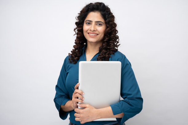 微笑的年轻女商人拿着笔记本电脑，看着相机在白色背景的股票照片图片下载