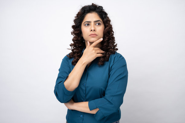 聪明和周到的年轻女子抱着她的下巴和思考的想法，在白色背景的股票照片图片下载