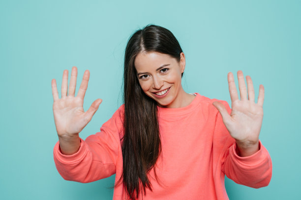 身穿粉红色毛衣的黑发长发女子露出幸福的笑容，双手摊开，满意地表示，隔离已经结束，无需戴防护手套。图片下载