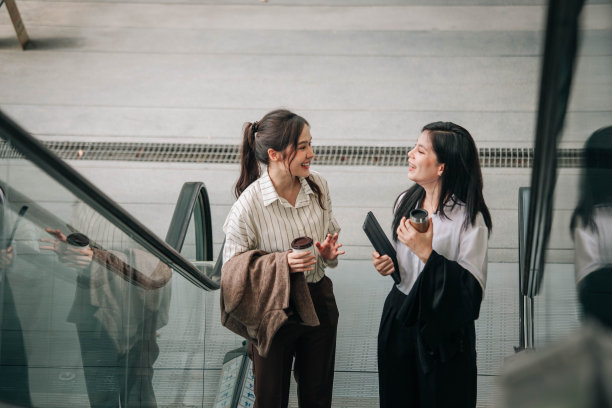 两个亚洲女人在上班的自动扶梯上聊天图片下载