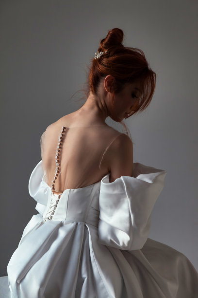 后视图时尚的德国新娘年轻漂亮的女士穿白色婚纱。时尚可爱的封面黑发女人在空灰色的房间摆姿势。时尚潮流风格美概念。复制广告文字空间图片下载