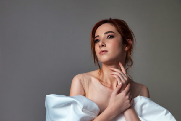 肖像时尚的德国新娘漂亮的女人在白色的婚纱摆姿势在灰色的背景，看向别处。时尚年轻可爱的封面黑发女士。时尚风格美理念。复制广告文字空间图片下载