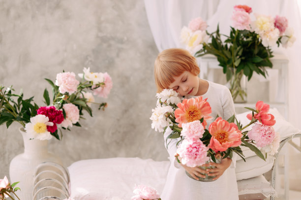 一个6-7岁的女孩穿着白色的裙子，手里拿着一朵花图片下载