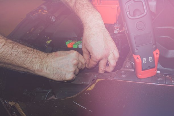 概念车服务，维修，调校，保养。汽车电工修理汽车电子设备上的问题。电工的手与电力单位在汽车特写。图片下载