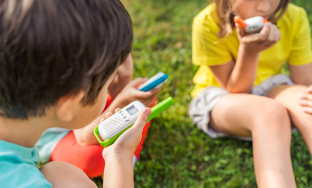 小孩子，女孩玩对讲机。带频道的对讲机。侦探和间谍的游戏。孩子们在远处交谈，传递信息。在森林、公园、徒步旅行中与家长交流。寻找迷路的人图片下载