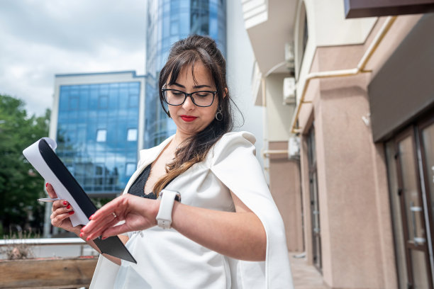穿着衬衫的女律师在附近等待同事时查看时间图片下载