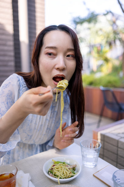 年轻女子在户外咖啡馆吃意大利面图片下载