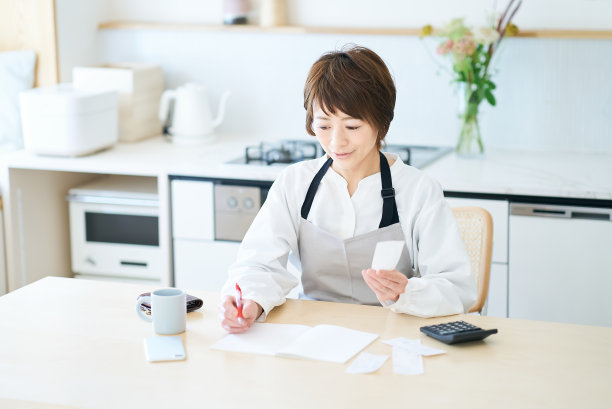 一个围着围裙的女人在检查收据图片下载