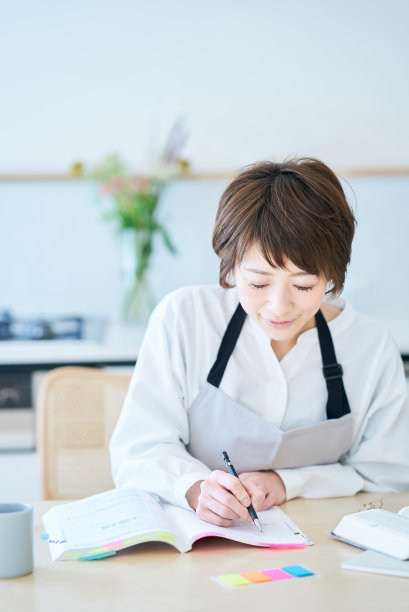 一个围着围裙的女人在学习课文图片下载