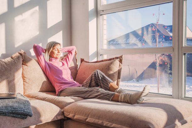 安详的女人家庭主妇躺椅上坐在沙发上，手放在脑后图片下载