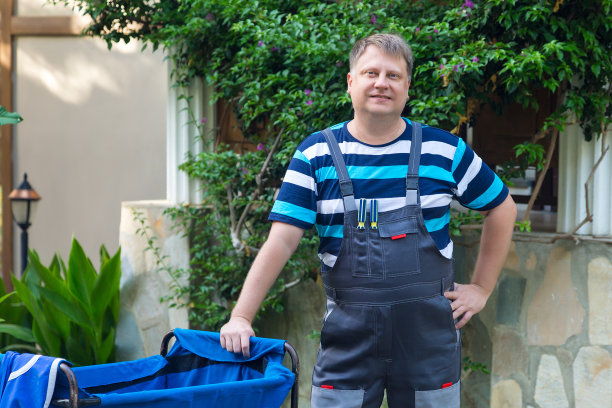 一个男人在城市街道上推着垃圾收集车图片下载