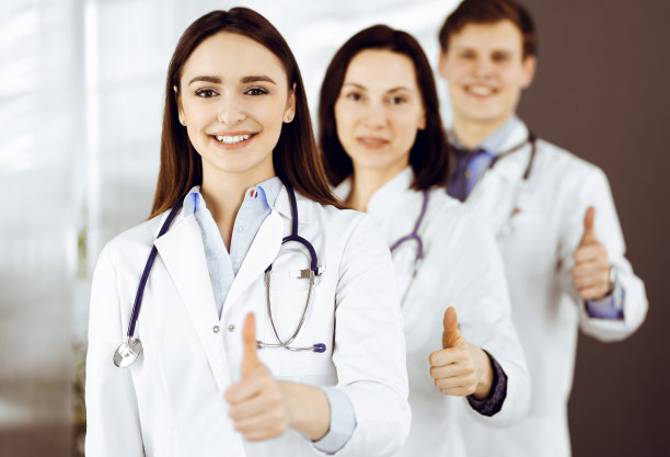一群年轻开朗的医生站在医院办公室里，竖起大拇指，随时准备帮助病人。医疗帮助医疗保险图片下载