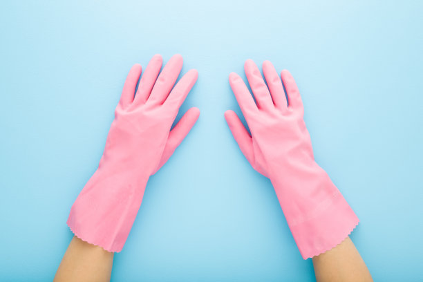 年轻的成年女子手在浅蓝色的桌子背景上的粉红色橡胶防护手套。特写镜头。视角镜头。自顶向下视图。图片下载