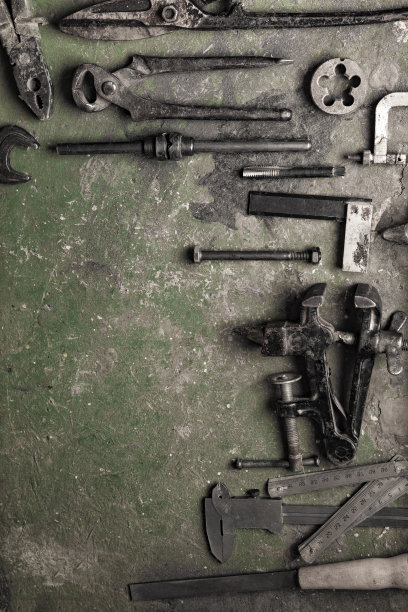 污迹斑斑的桌子上，工作背景上破旧的金属加工工具(加工跨工序)图片下载