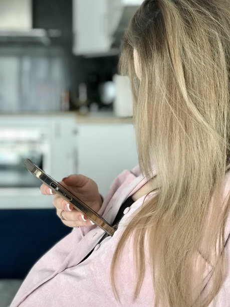 年轻漂亮的孕妇，长头发，粉红色衬衫，手里拿着一杯酸奶，看着手机图片下载