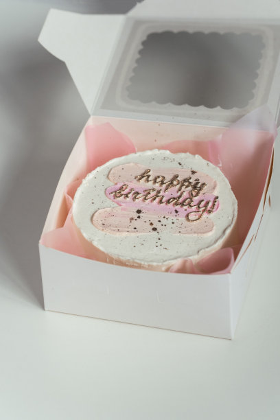 小韩式潮流便当蛋糕在白色的礼盒在白色的背景。蛋糕上面有生日快乐的文字图片下载