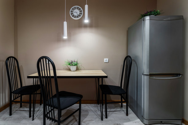 餐桌靠墙而立，黑色金属椅和一束鲜花立在餐桌上，局部照明用灯具图片下载