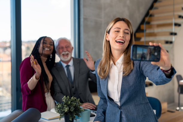 年轻迷人的女商人站在办公室与她的同事自拍图片下载