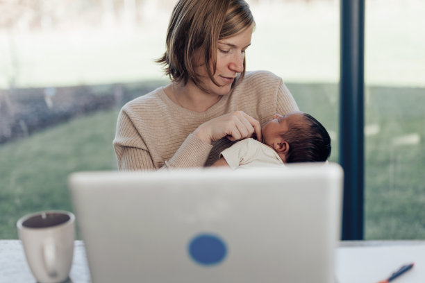 职场母亲在家中远程照顾刚出生的孩子图片下载