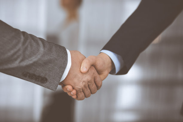身着办公套装的商务人士站着握手，特写镜头。商务沟通理念。握手与营销图片下载