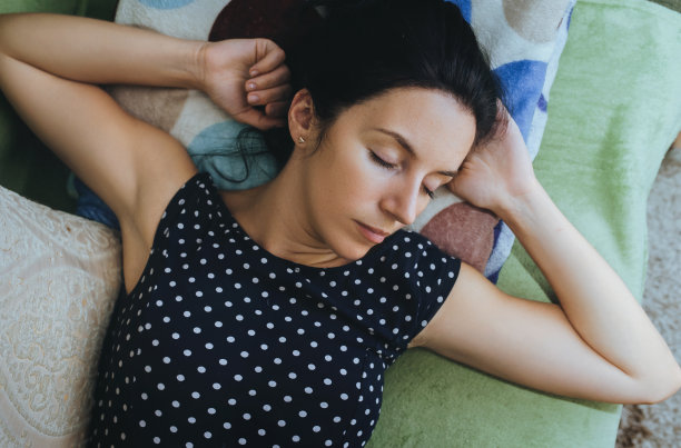 一个年轻的白种人黑发女孩躺在格子上休息。白天睡眠，放松和休息。从上面看。图片下载