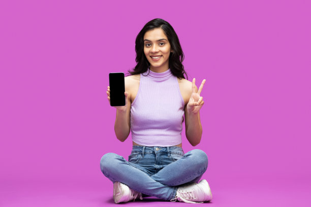 开朗的年轻女孩迷人的照片，迷人的开朗，手里拿着新细胞孤立的紫色背景的股票照片图片下载