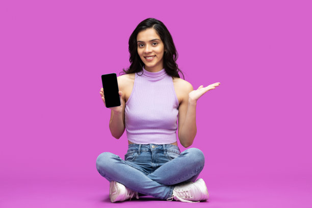 开朗的年轻女孩迷人的照片，迷人的开朗，手里拿着新细胞孤立的紫色背景的股票照片图片下载