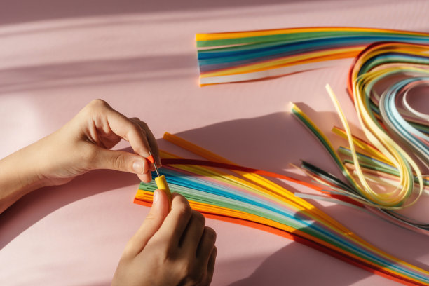 纸张和羽毛工具在粉红色的背景与手和空间的文字和设计。图片下载