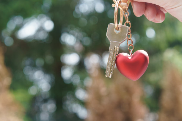 房子钥匙在手上，红色心形钥匙扣。图片下载