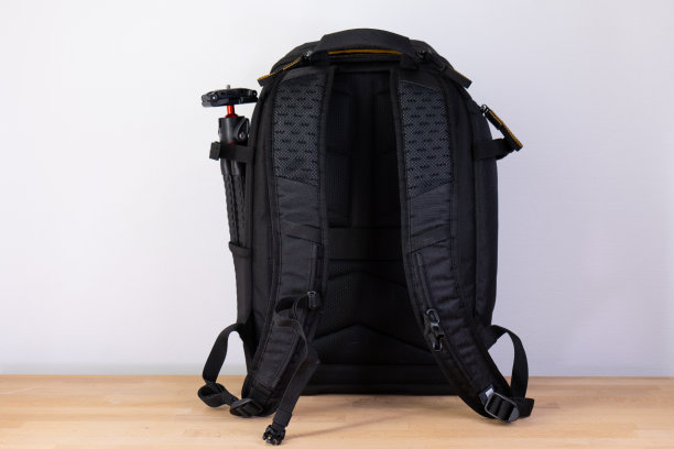 照片的背包。黑色相机背包站在木桌背面。图片下载