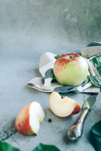 新鲜收获的成熟绿红色有机苹果放在餐巾或毛巾上，刀放在桌子上，留有复制空间。图片下载