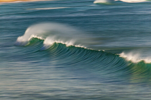 在近海风的作用下，海浪在海滩上破碎的模糊运动图片下载